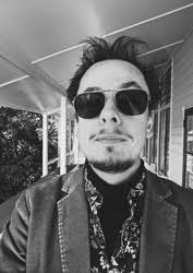Black-and-white photo of Mirko in sunglasses and a blazer, on a veranda