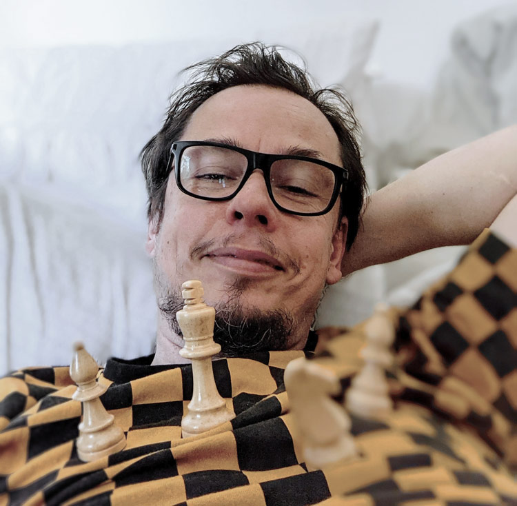 Mirko lying back with chess pieces on a chequered top